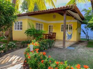 a yellow house with a table and flowers at La Dolce Vita Flat & Pousada in Praia do Frances