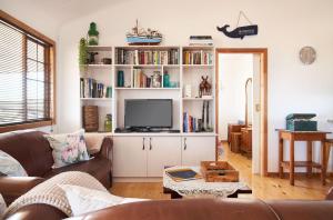 sala de estar con sofá y TV en Dogstone Cottage en Hondeklipbaai