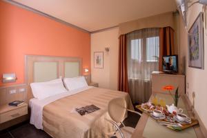 una camera d'albergo con un letto e un tavolo con un piatto di cibo di Hotel Mediterraneo a Livorno