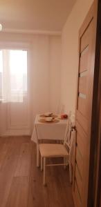 ein weißes Esszimmer mit einem Tisch und einem Fenster in der Unterkunft Аблайхана 1/3 in Kökschetau