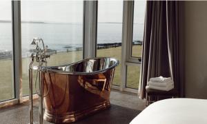 a bathroom with a tub in front of a window at Armada Hotel in Spanish Point