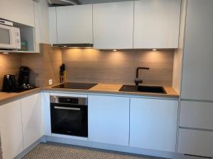 a kitchen with white cabinets and a sink at Residentie Hippocampe in Wenduine