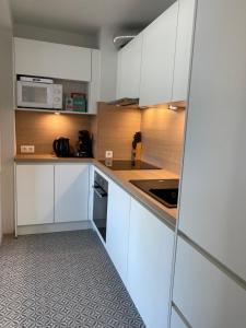 a kitchen with white cabinets and a microwave at Residentie Hippocampe in Wenduine