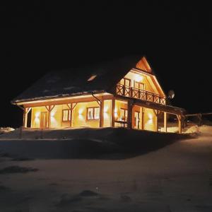a house lit up at night with snow on it at Willa Kaszubiak in Ostrzyce