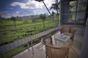 Un balcón con 2 sillas y una mesa con vistas. en Jyothis Retreat en Palakkad