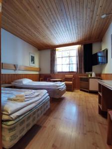 two beds in a room with a wooden ceiling at Saariselkä Inn Majatalo Panimo in Saariselka