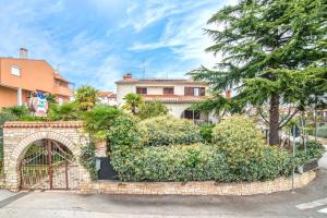 a brick fence with bushes in front of a house at Apartments Volte Rovigno in Rovinj