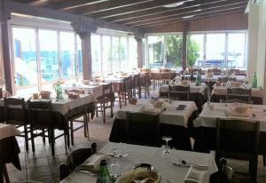 un ristorante con tavoli e sedie bianchi e finestre di Hotel Arborea a Lido di Jesolo