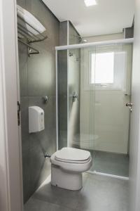 a bathroom with a toilet and a glass shower at Plaza Inn Trevo Sorocaba in Sorocaba