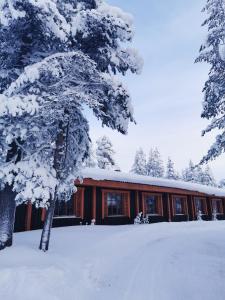 un edificio coperto di neve accanto a un albero di Saariselkä Inn Majatalo Panimo a Saariselka