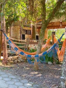 a hammock hanging from trees in front of a house at Recanto Marina in Guarda do Embaú