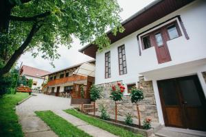 a white house with a tree and a sidewalk at Gyöngyvirág Panzió in Lupeni