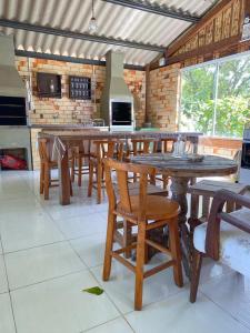 uma cozinha com mesas e cadeiras de madeira num quarto em Recanto Marina em Guarda do Embaú