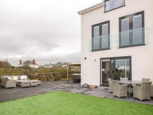 a white house with a patio and grass at The Sandy Bee in Benllech