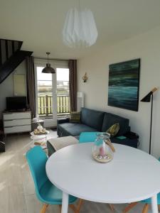 uma sala de estar com uma mesa branca e cadeiras azuis em La Naturelle Duplex 90 em Wimereux