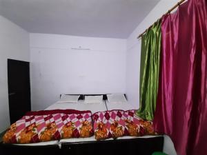 a bedroom with a bed with pink and green curtains at Hotel Himalayan Dews Ukhimath in Ukhimath