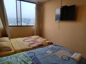 a hotel room with two beds and a flat screen tv at apartamento CAA pardo in Lima
