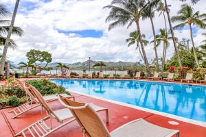 a pool at a resort with chairs and palm trees at Lae Nani 326 in Kapaa