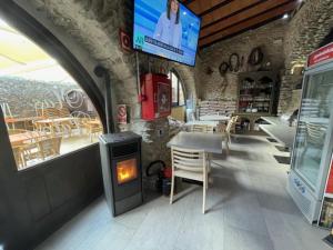 a room with a fireplace and a tv and tables and chairs at Hotel Mas Palou in Roses