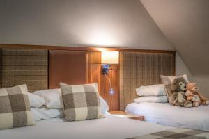 two beds with stuffed animals on them in a room at Mackays Hotel in Wick