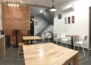 a room with tables and chairs and a brick wall at Just Austin Guesthouse in Ipoh