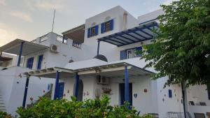 a white house with blue columns and windows at Galazio Kyma in Agios Ioannis