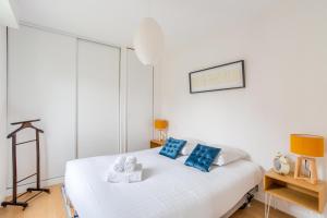 1 dormitorio con cama blanca y almohadas azules en L'Astrolabe, en Dinard