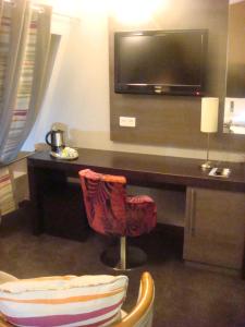 a living room with a tv and a chair at Holiday Inn Paris Montmartre, an IHG Hotel in Paris