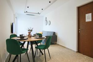 een eetkamer met een tafel en groene stoelen bij Phaedrus Living: Seaside Luxury Flat Lighthouse 69 in Paphos City