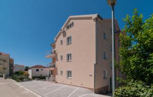 a tall pink building with a parking lot at Apartments Island Beat in Supetar
