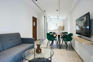 een woonkamer met een bank en een tafel met stoelen bij Phaedrus Living: Seaside Luxury Flat Lighthouse 69 in Paphos City
