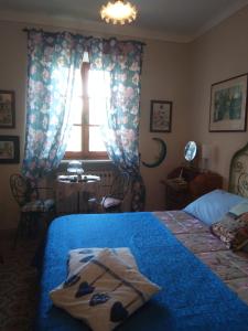 1 dormitorio con cama con sábanas azules y ventana en L'apparita Camere, en Pienza