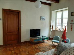 a living room with a television and a table with a chair at N¨°1 SCHONGAUER GITE DE CHARME CENTRE TOURISTIQUE COLMAR in Colmar