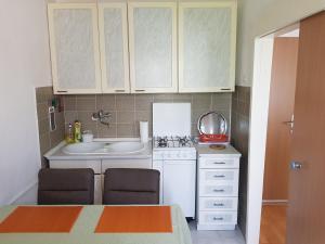 Elle comprend une petite cuisine avec des placards blancs et un évier. dans l'établissement Apartments Nikol, à Lopar