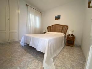 Un dormitorio con una cama con una manta blanca. en Apartamentos Casablanca Altamar, en Alcossebre