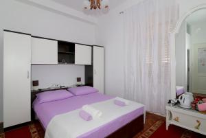 a bedroom with a large bed with purple pillows at Rooms&Studios Rina in Dubrovnik