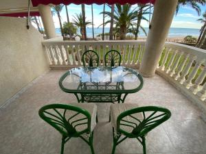 Apartamentos Casablanca Altamar في الكوسيبري: طاولة زجاجية وكراسي على شرفة مع الشاطئ