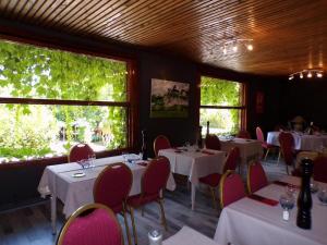 a restaurant with white tables and chairs and windows at Domaine de Lacave in Lacave