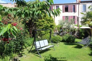 un banc à bascule dans un jardin avec un bâtiment dans l'établissement Maison Prades Chambre d'Hôtes, à Prades