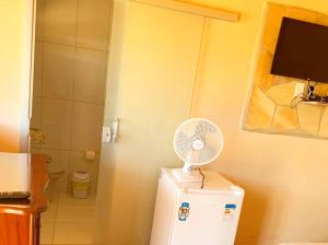 a white fan sitting on top of a refrigerator at Pousada e Chales Por do Sol in São Thomé das Letras