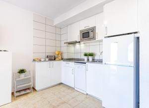 a white kitchen with white cabinets and appliances at Apart-rent Apartment Av Rhode 3º 2008 in Roses