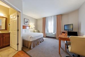 a hotel room with a bed and a desk and a television at Extended Stay America Suites - McAlester - Hwy 69 in McAlester