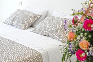 a white bed with pillows and a bouquet of flowers at Il Barilotto in Positano