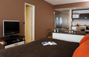 a room with a bed and a tv and a kitchen at Ayres Recoleta Uriburu in Buenos Aires