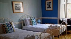 two beds in a room with blue walls at The Top House Inn in Lizard