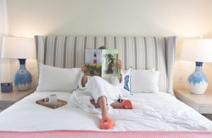 a person laying on a bed with a book at The Nantucket Hotel & Resort in Nantucket