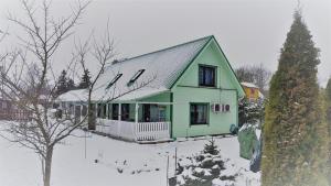 a green house in the snow with a tree at Aare kodumajutus in Tammiku