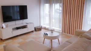 ein Wohnzimmer mit einem weißen Sofa und einem TV in der Unterkunft TOPO Apartment in Ponta Delgada