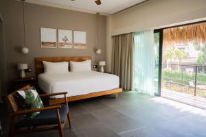 a bedroom with a bed and a chair and a window at San Trópico Boutique Hotel & Peaceful Escape in Puerto Vallarta