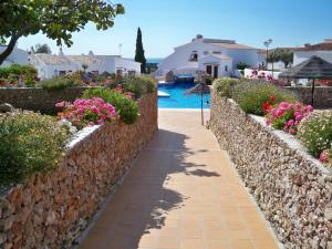 a stone wall next to a swimming pool with flowers at El Capistrano Sur in Nerja
